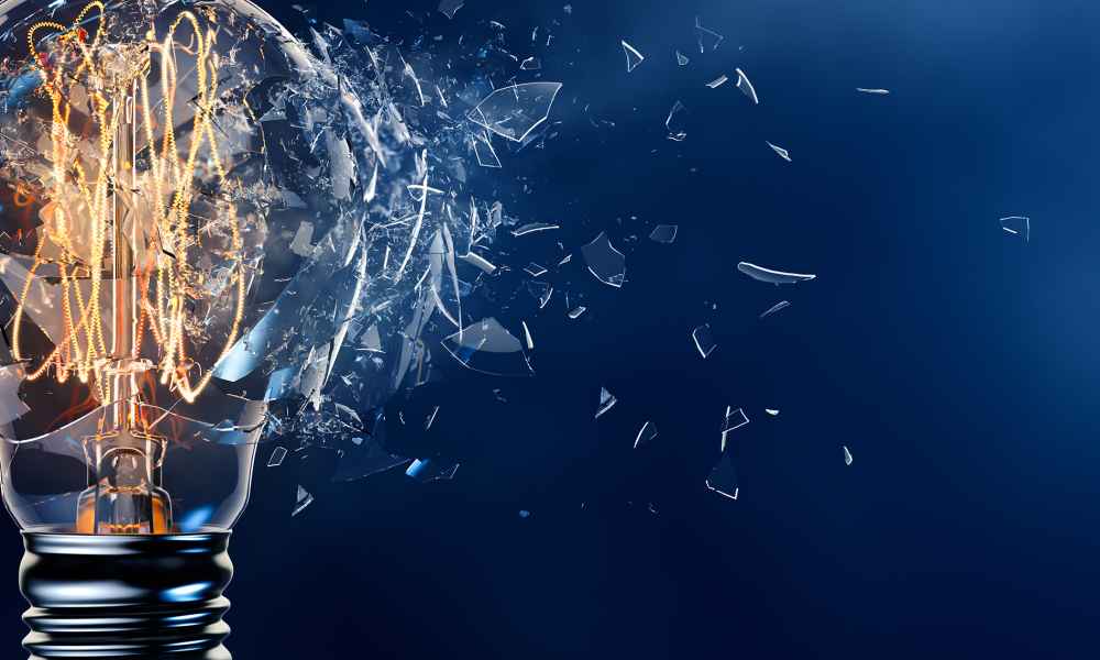Exploding light bulb with shattered glass on empty blue background