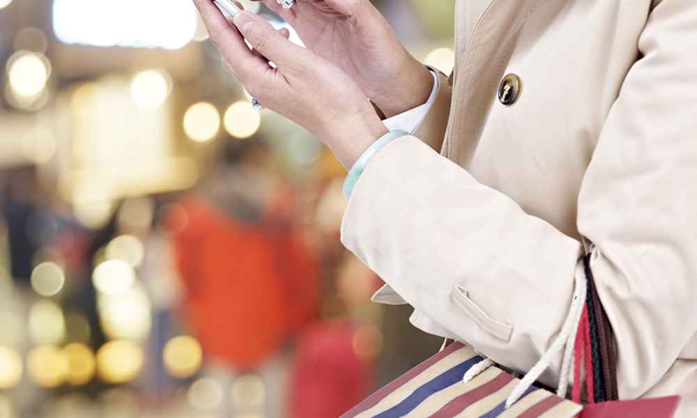 woman touching mobile phone carrying shopping bags