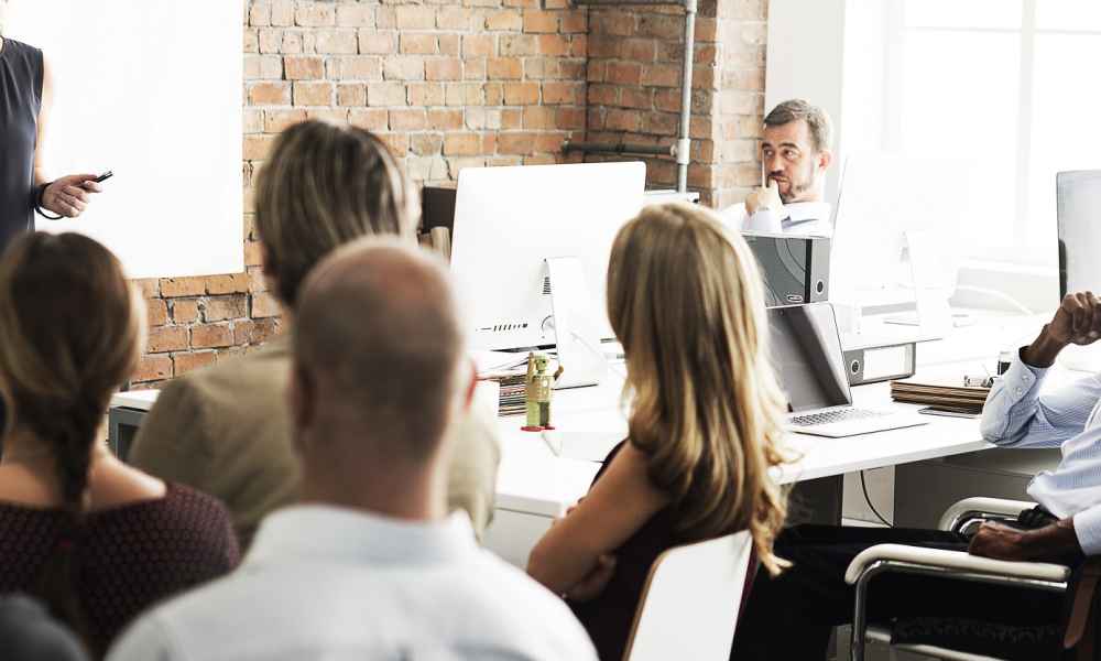 people at table with person by whiteboard