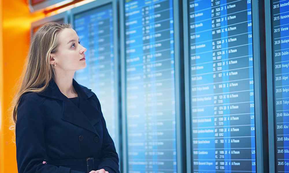 woman looking at arrival and departure data on digital screens